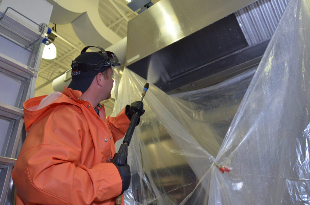 HOODZ technician spraying a kitchen hood kitchen maintenance franchise